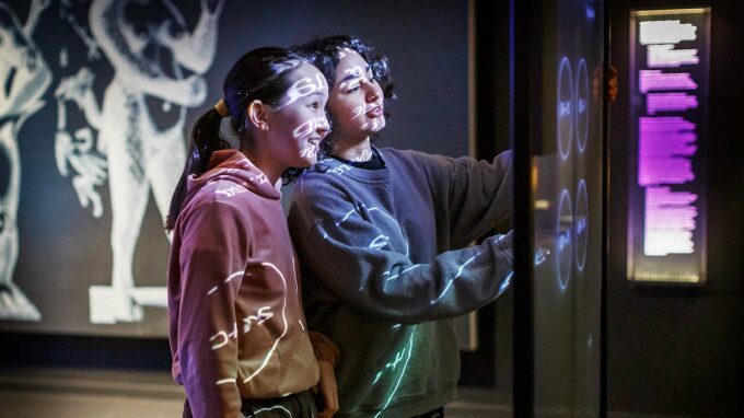 unga tjejer står framför en digital skärm