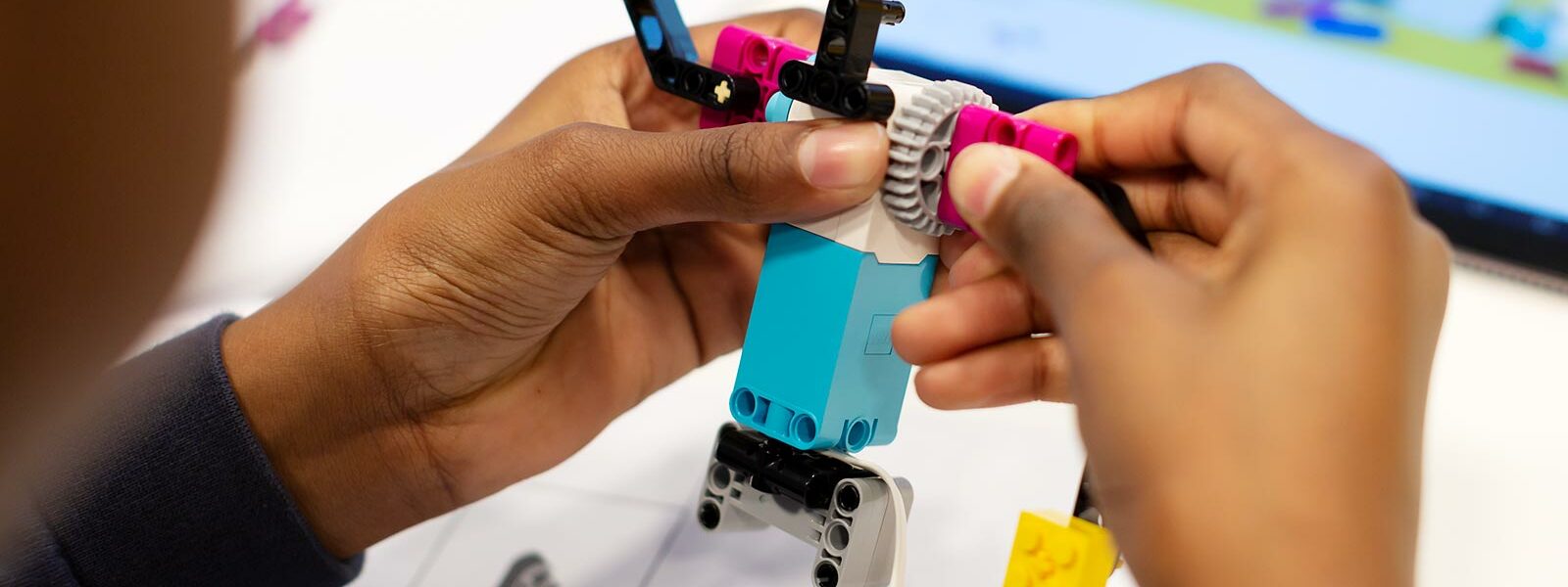 händer som bygger en robot gjord av lego