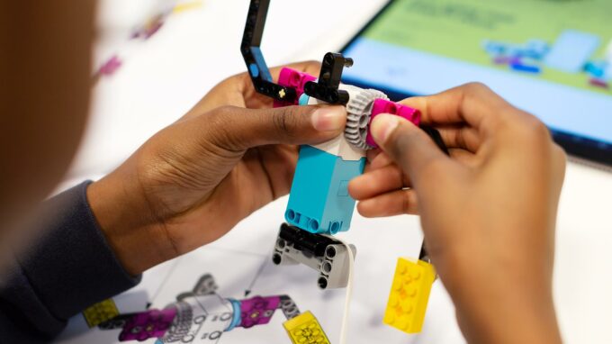händer som bygger en robot gjord av lego