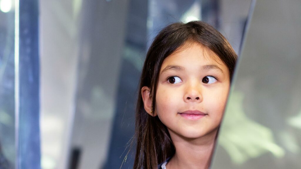 liten tjej med mörkbrunt hår och bruna ögon som tittar fram