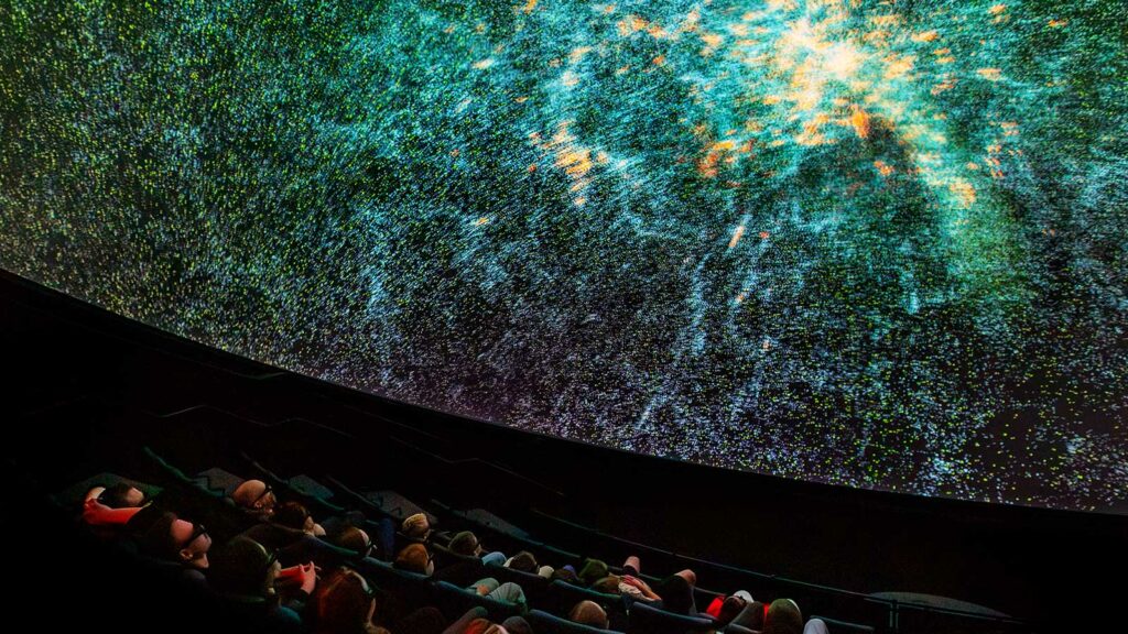 Publik som sitter framför en bildprojektor som visar rymden