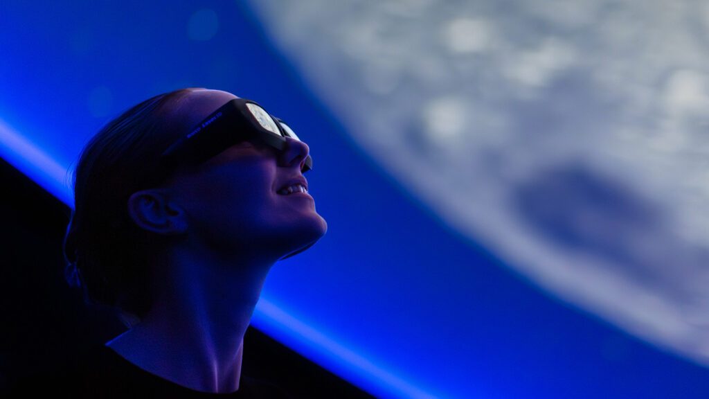 tjej som har på sig vr-glasögon och tittar ut mot månen i 3d