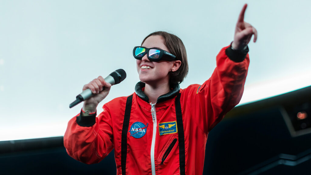 Tjej med mikrofon klädd som astronaut.