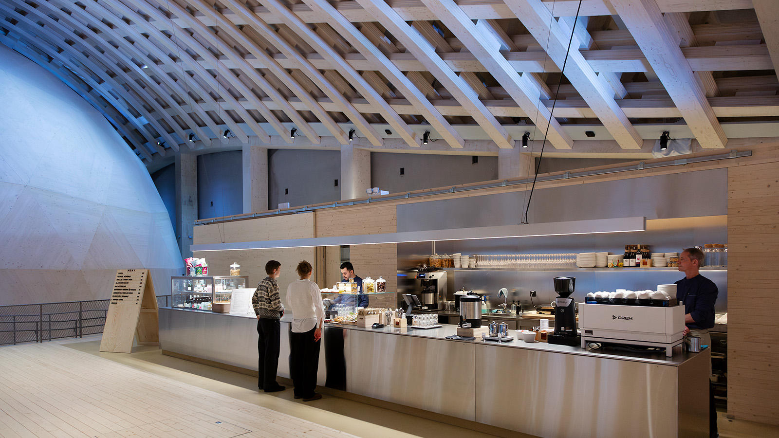 Person i en trähall som står i ett cafe och betalar