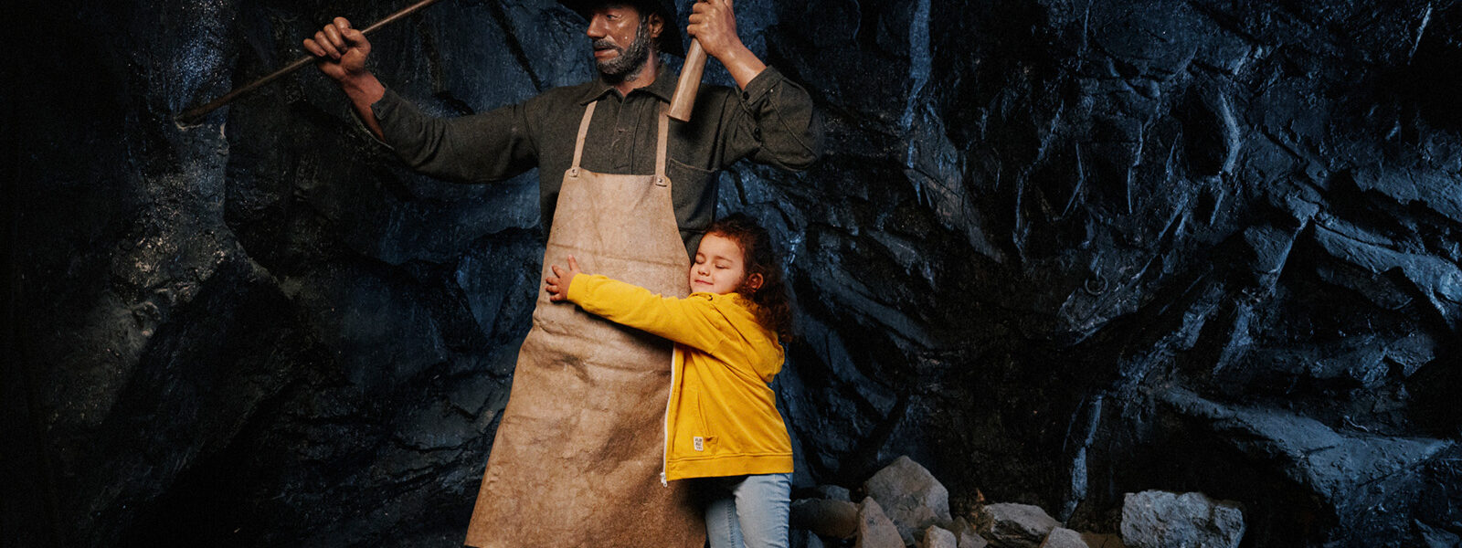 litet barn kramar om en vaxdocka som föreställer en gruvarbetare