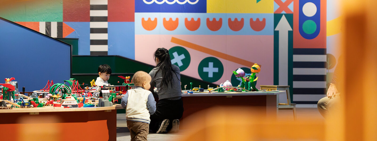 Mamma med son och ett annat barn somspringer i förgrunden